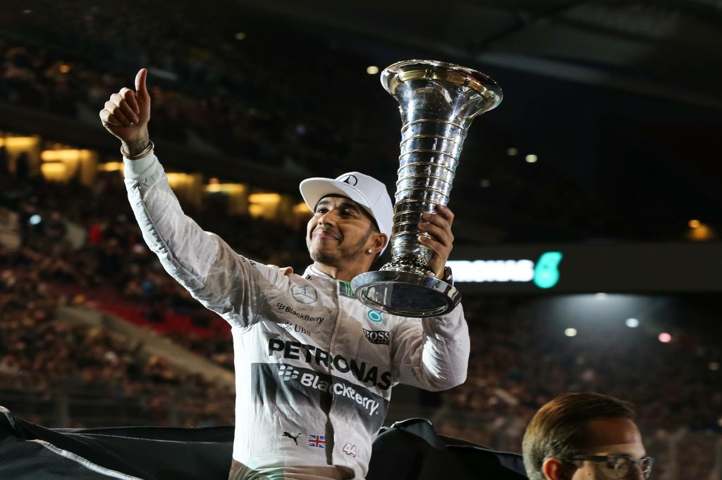 Lewis Hamilton feiert mit einem Pokal in der Hand
