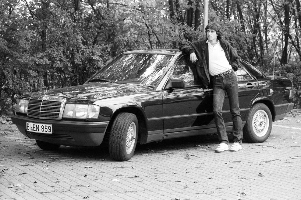 Junger Mann lehnt an schwarzem Mercedes