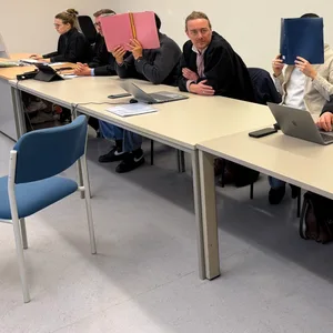 Die drei Anegklagten sitzen mit Mappen vor dem Gesicht neben ihren Verteidigern.