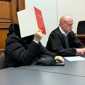 Der Angeklagte Patrik D. sitzt mit einer Mappe vor dem Gesicht neben seinem Verteidiger
