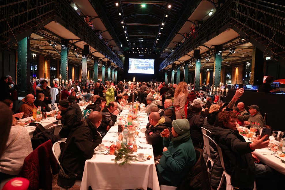 Menschen sitzen an Tischen in der Fischauktionshalle