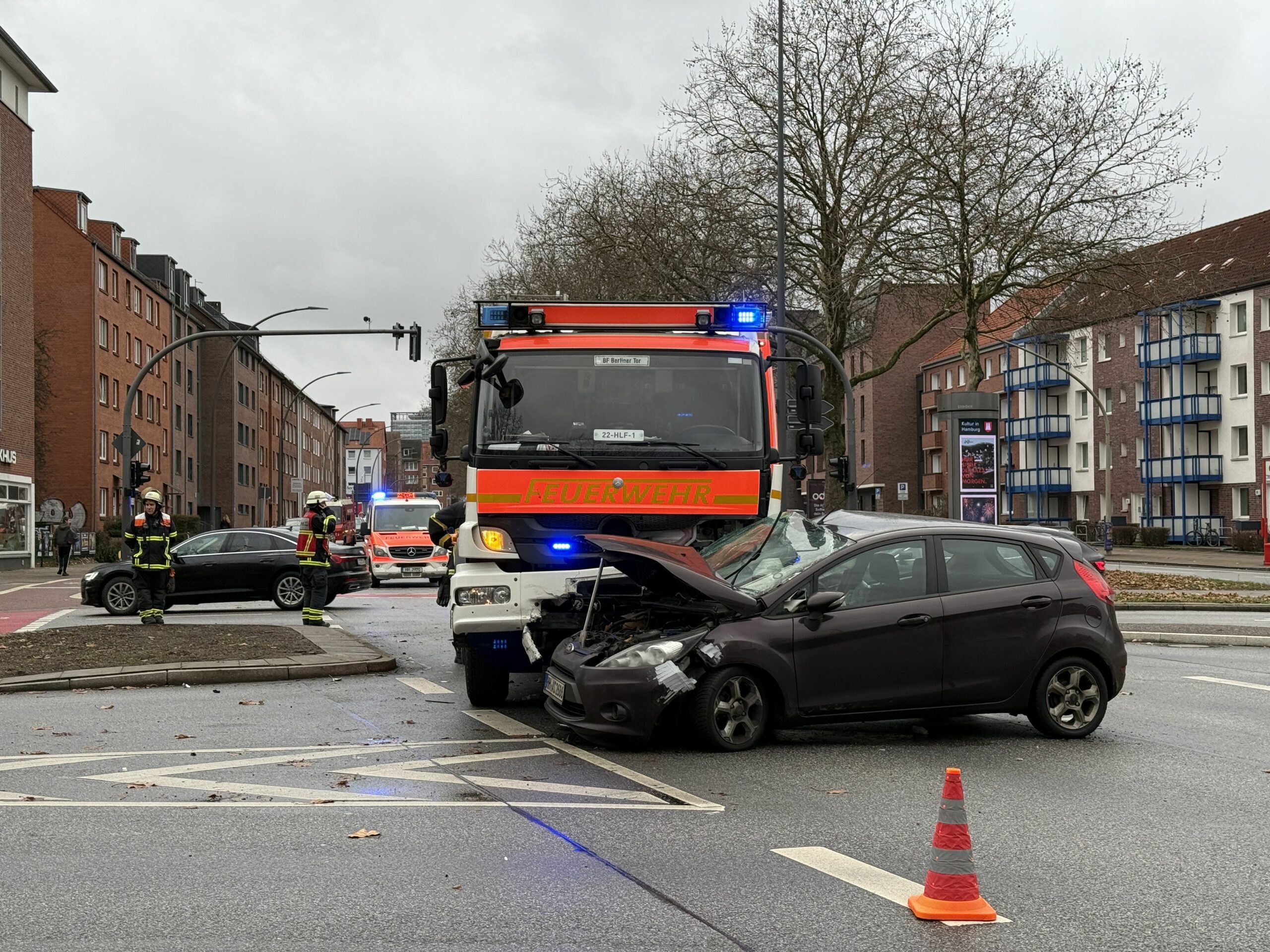 Schwarzer Unfallwagen mit Feuerwehrauto auf einer Kreuzung