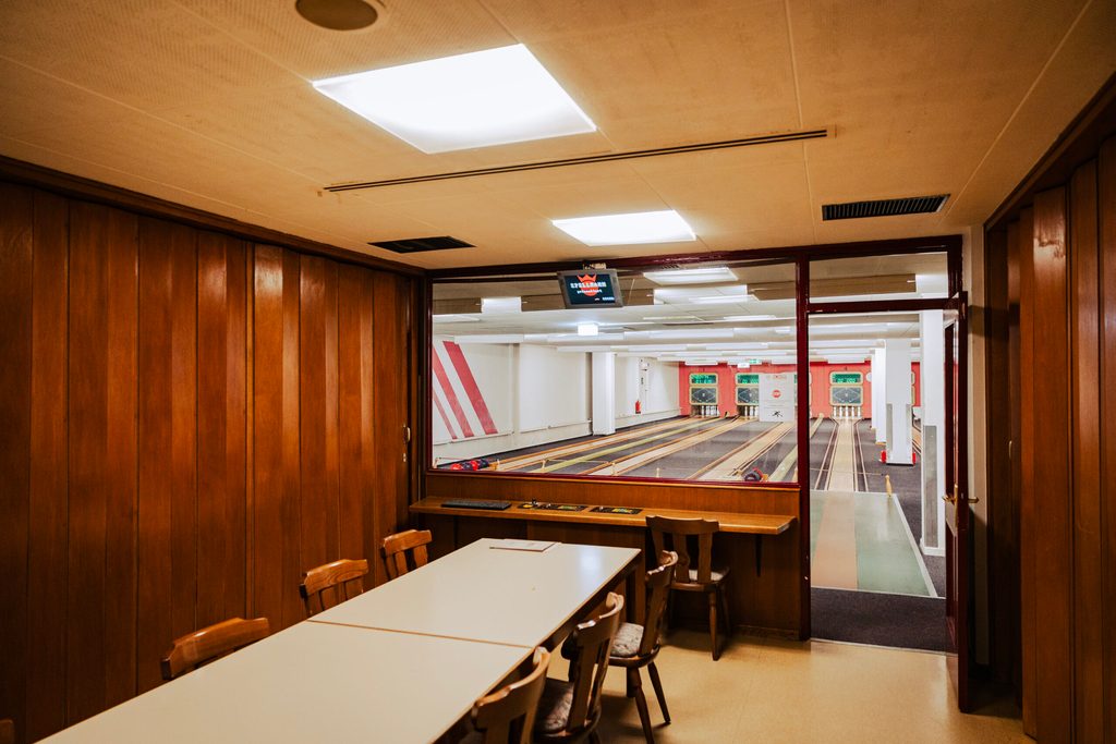 Blick aus einer Kabine: Schlichte Kegelbahnen in weißem Licht.