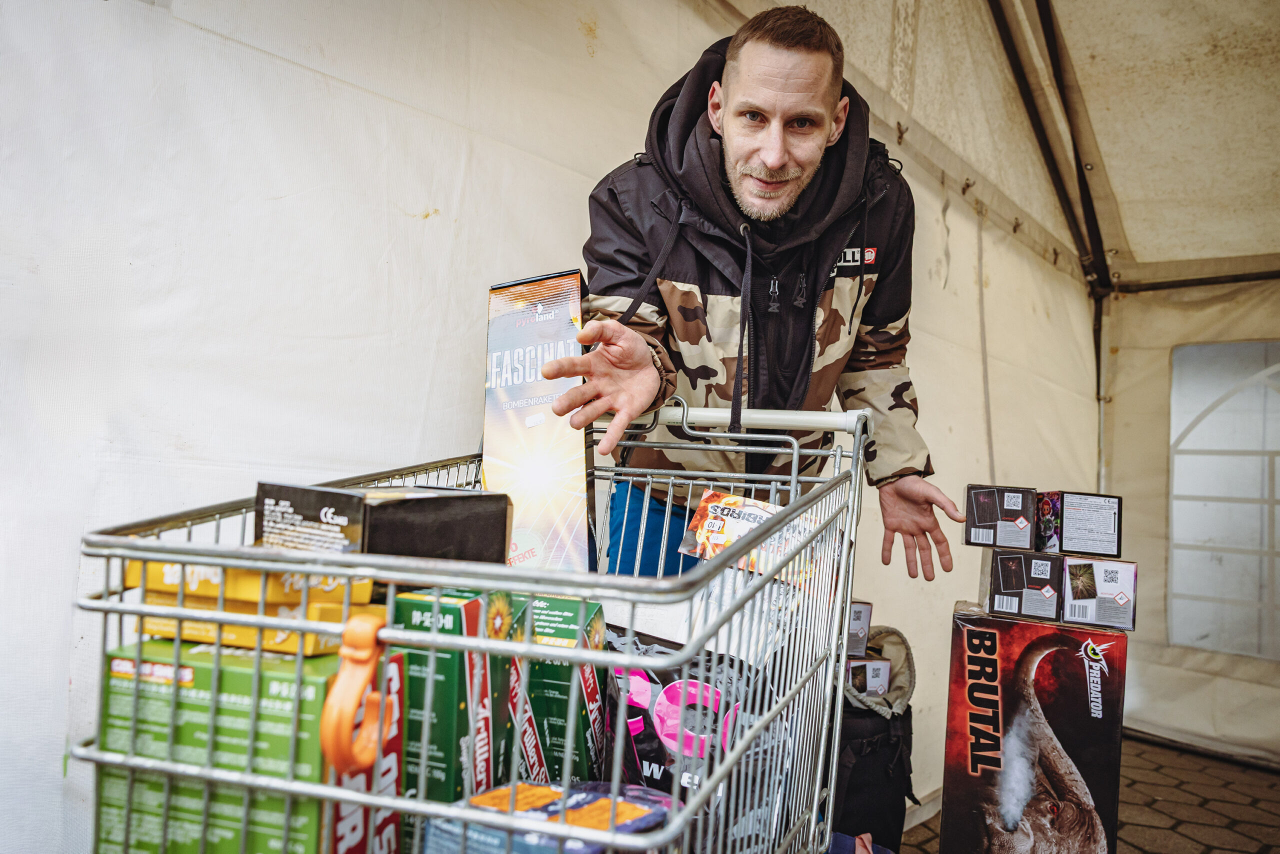 Mann beugt sich über einen Einkaufswagen voller Feuerwerk