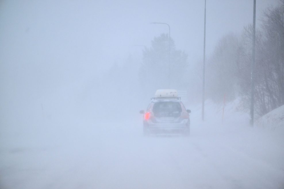 Ein Auto fährt bei Nebel durch eine Schneelandschaft im vom Sturm gezeichneten Schweden.