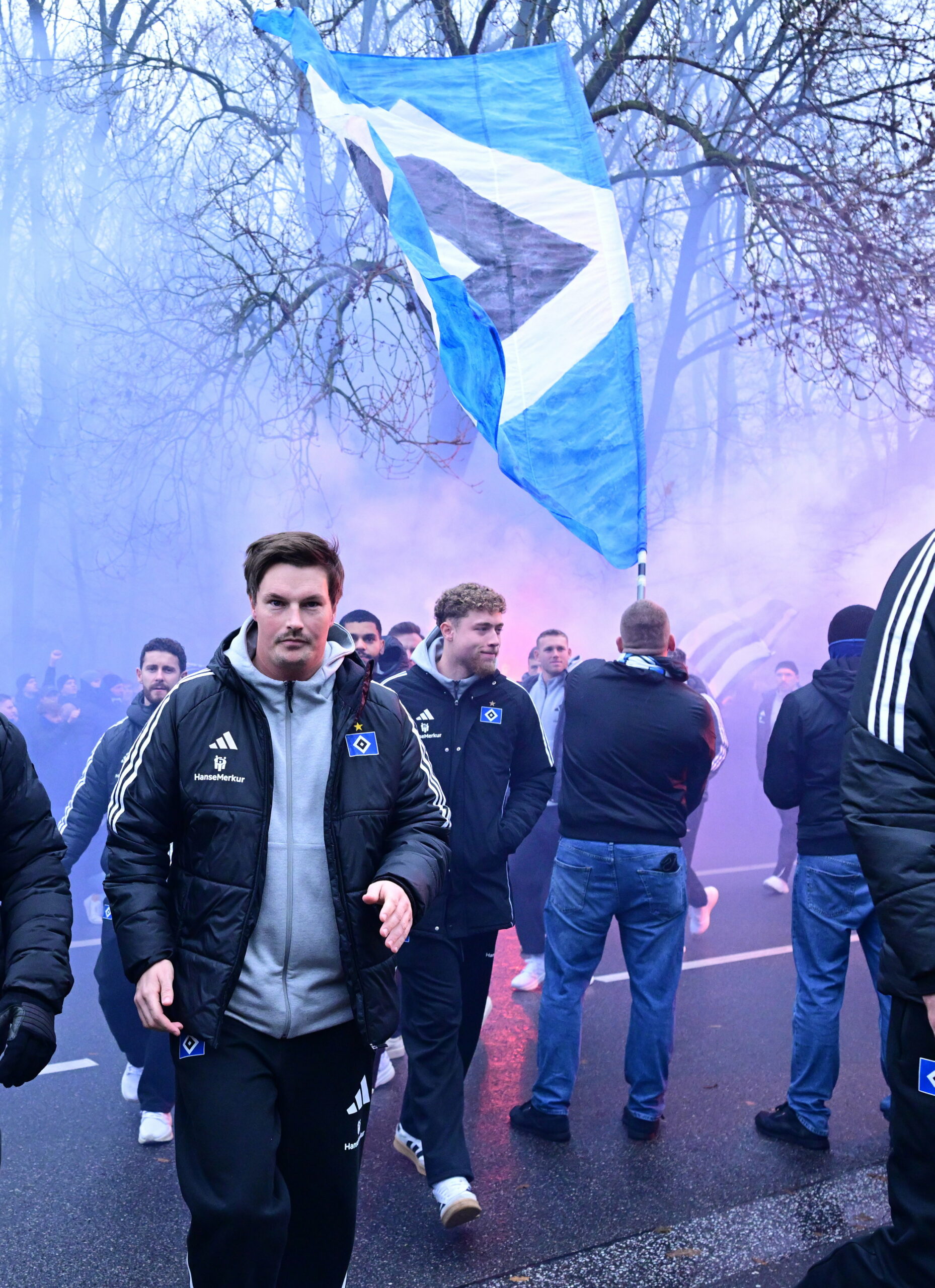 Merlin Polzin geht bei der Busankunft am HSV-Stadion durch dichten Rauch