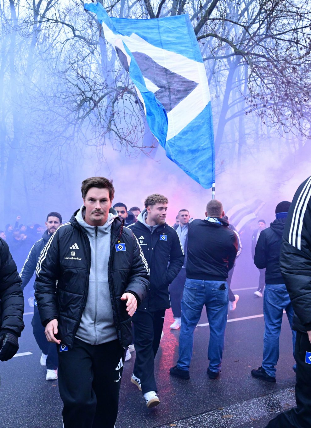Merlin Polzin geht bei der Busankunft am HSV-Stadion durch dichten Rauch