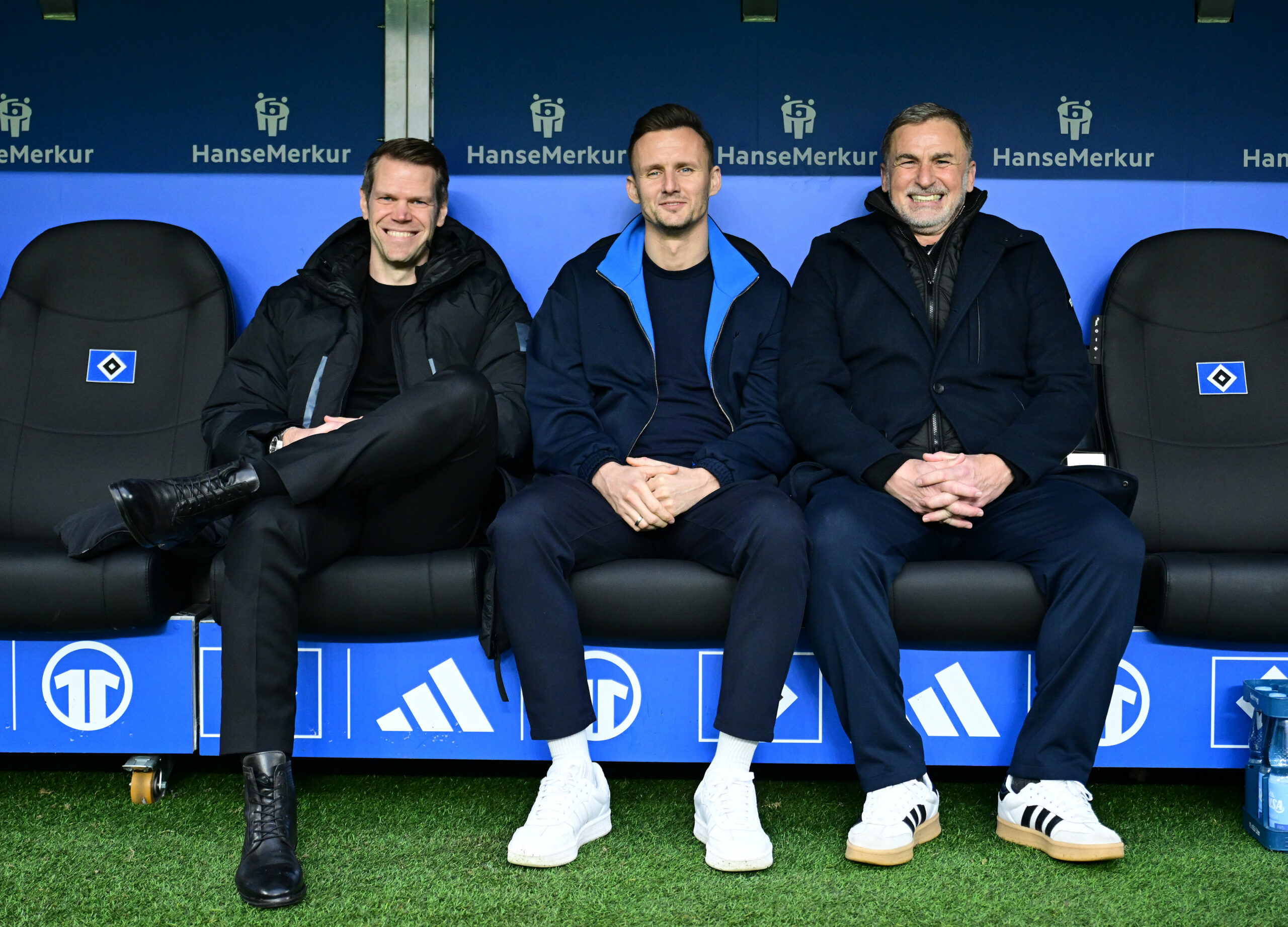 Eric Huwer, Claus Costa und Stefan Kuntz lächeln nebeneinander auf der Auswechselbank