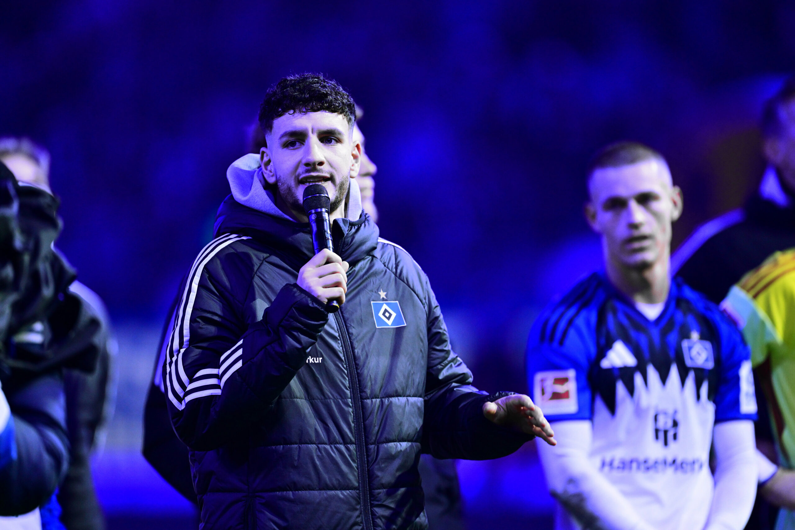 Daniel Elfadli spricht mit dem Mikrofon in der Hand zu den HSV-Fans.