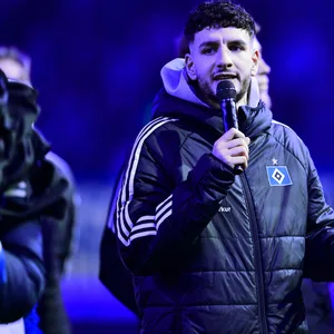 Daniel Elfadli spricht mit dem Mikrofon in der Hand zu den HSV-Fans.