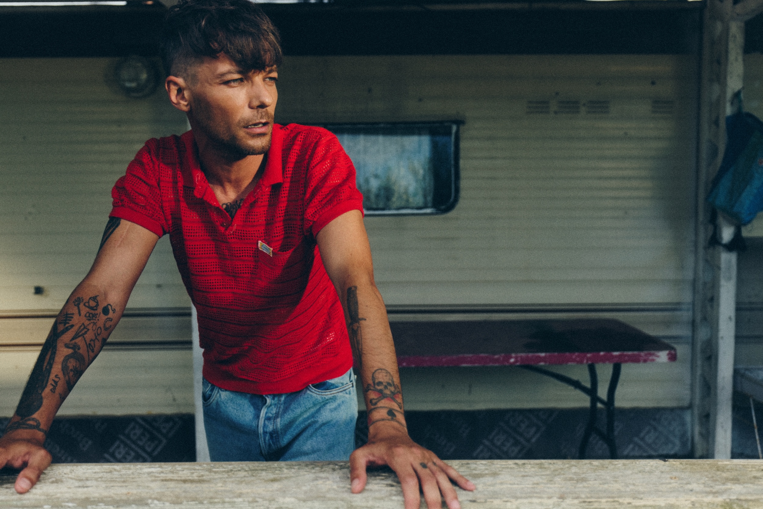 Er steht draußen, stützt sich vielleicht auf einen Tisch und schaut zur Seite