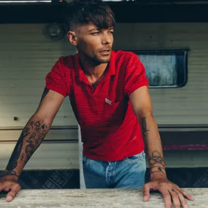 Er steht draußen, stützt sich vielleicht auf einen Tisch und schaut zur Seite