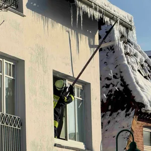 Ein Feuerwehrmann schlägt gefährliche Eiszapfen von einem Dach in Horneburg bei Hamburg ab.