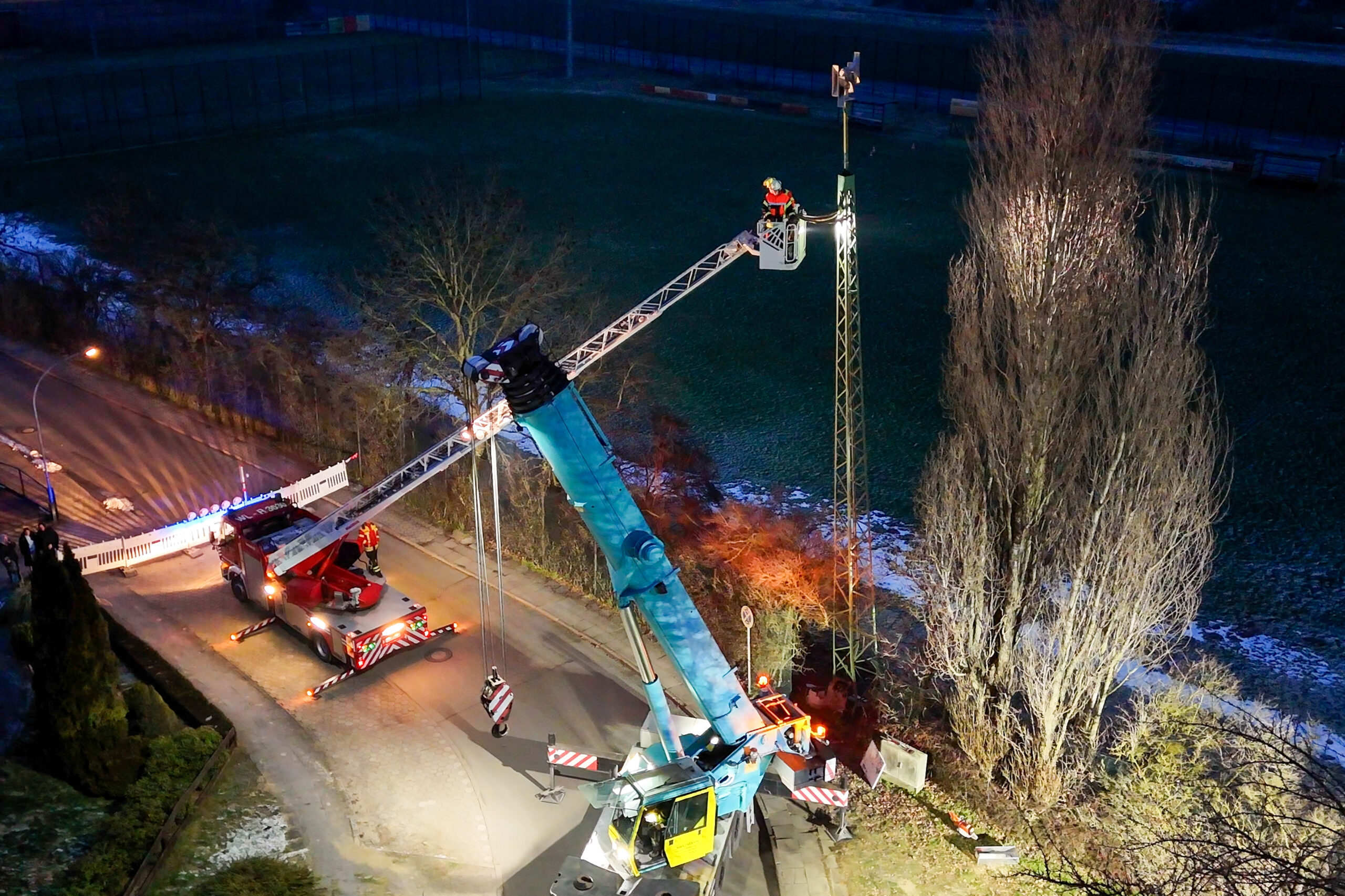 Eine Person ist auf einem Kran, der zum Sirenenmast reicht.