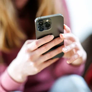 Eine Frau hält ein Handy in der Hand.