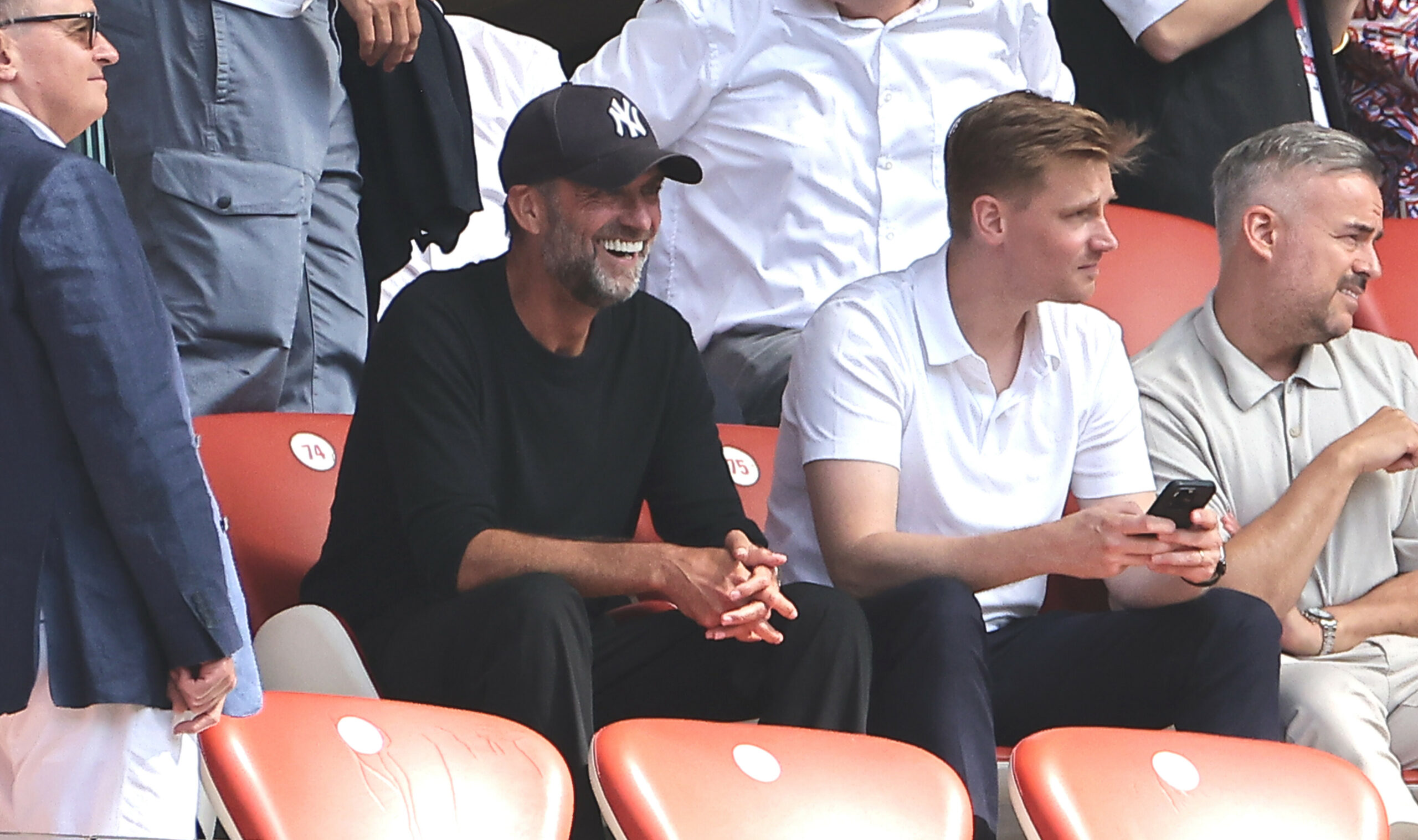 Jürgen Klopp sitzt auf der Tribüne und lacht