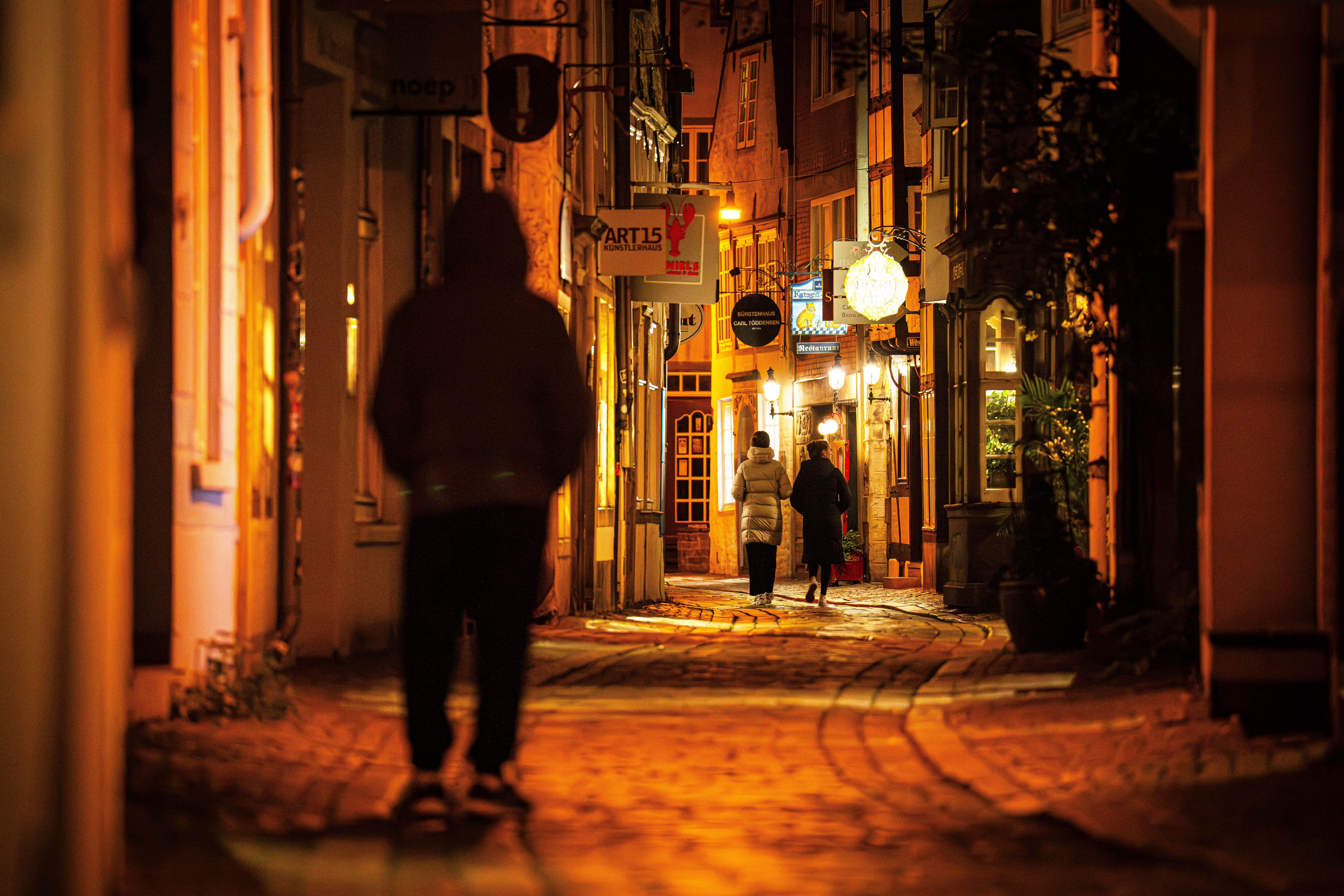 Passanten laufen in einer dunklen Gasse