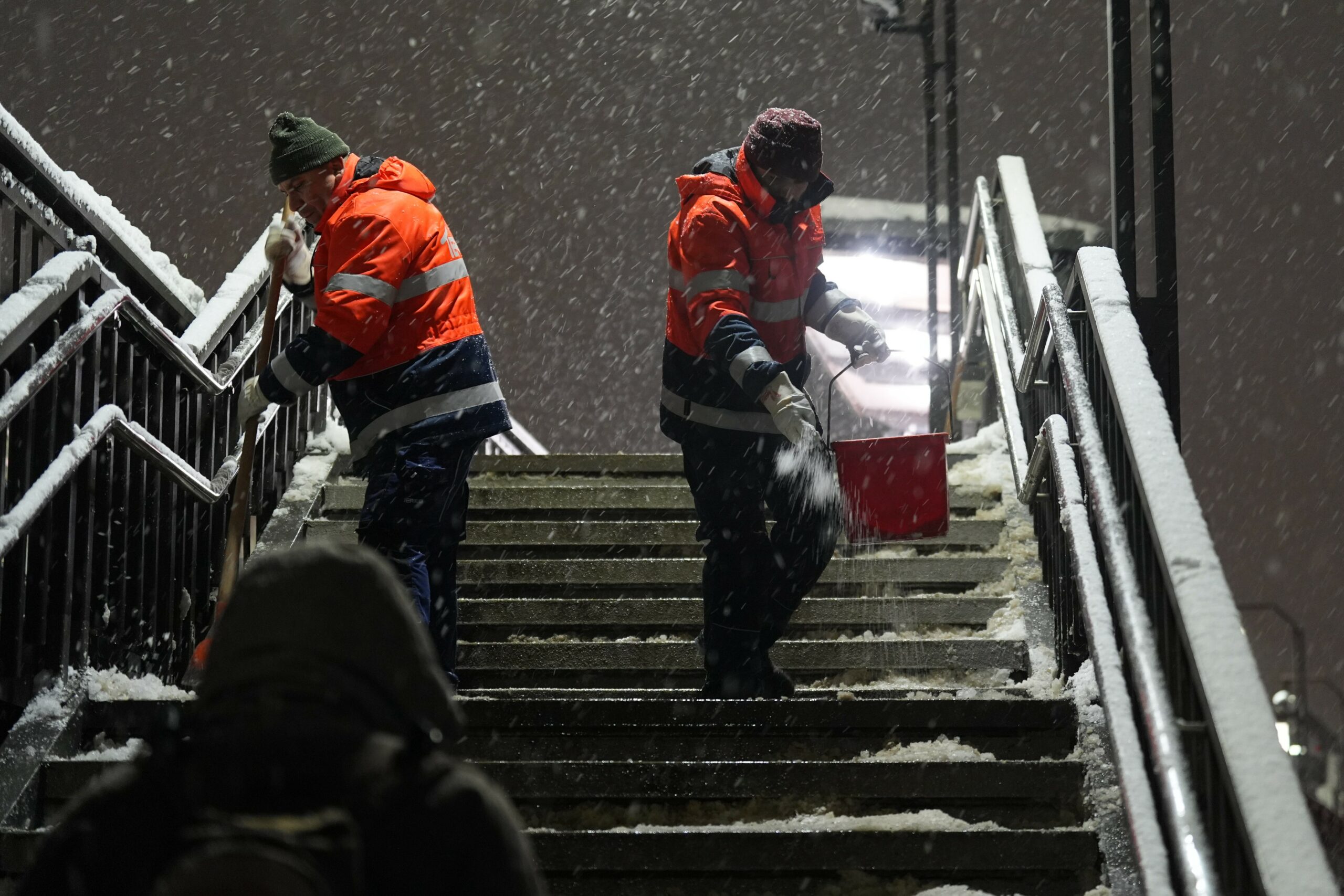 Mitarbeiter streuen die Treppenstufen an der U-Bahnstation Baumwall im Hamburger Hafen.