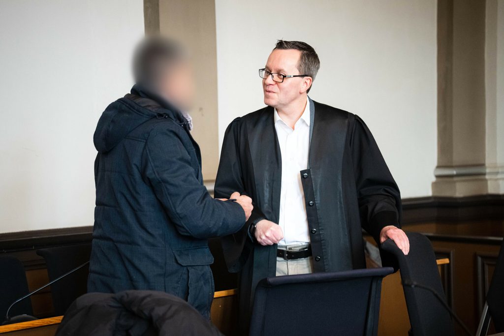 Der Angeklagte spricht vor Prozessbeginn mit seinem Anwalt René Lancker (r).