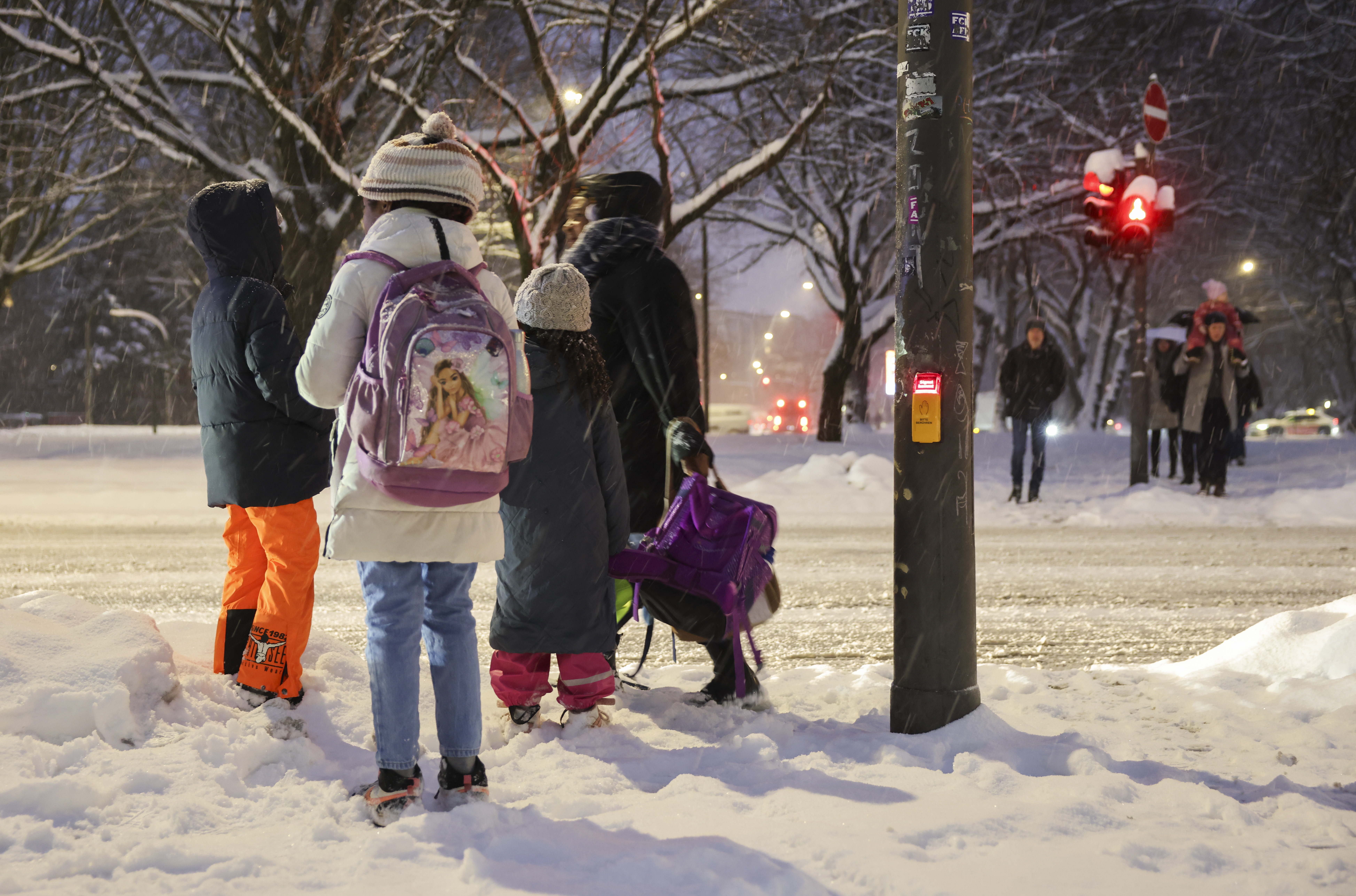 Im Schnee sind Kinder auf dem Weg zur Schule.