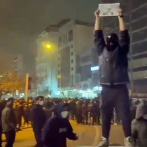 Ein maskierter Demonstrant in Teheran bei den Massenprotesten gegen die Regierung im Iran. Er hält ein Bild des ehemaligen iranischen Kronprinzen Reza Pahlavi.