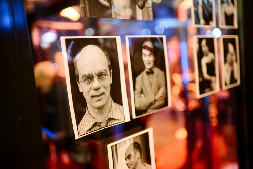 Schwarz-weiße Portraitfotos von Corny Littmann hängen an einer Fensterscheibe.