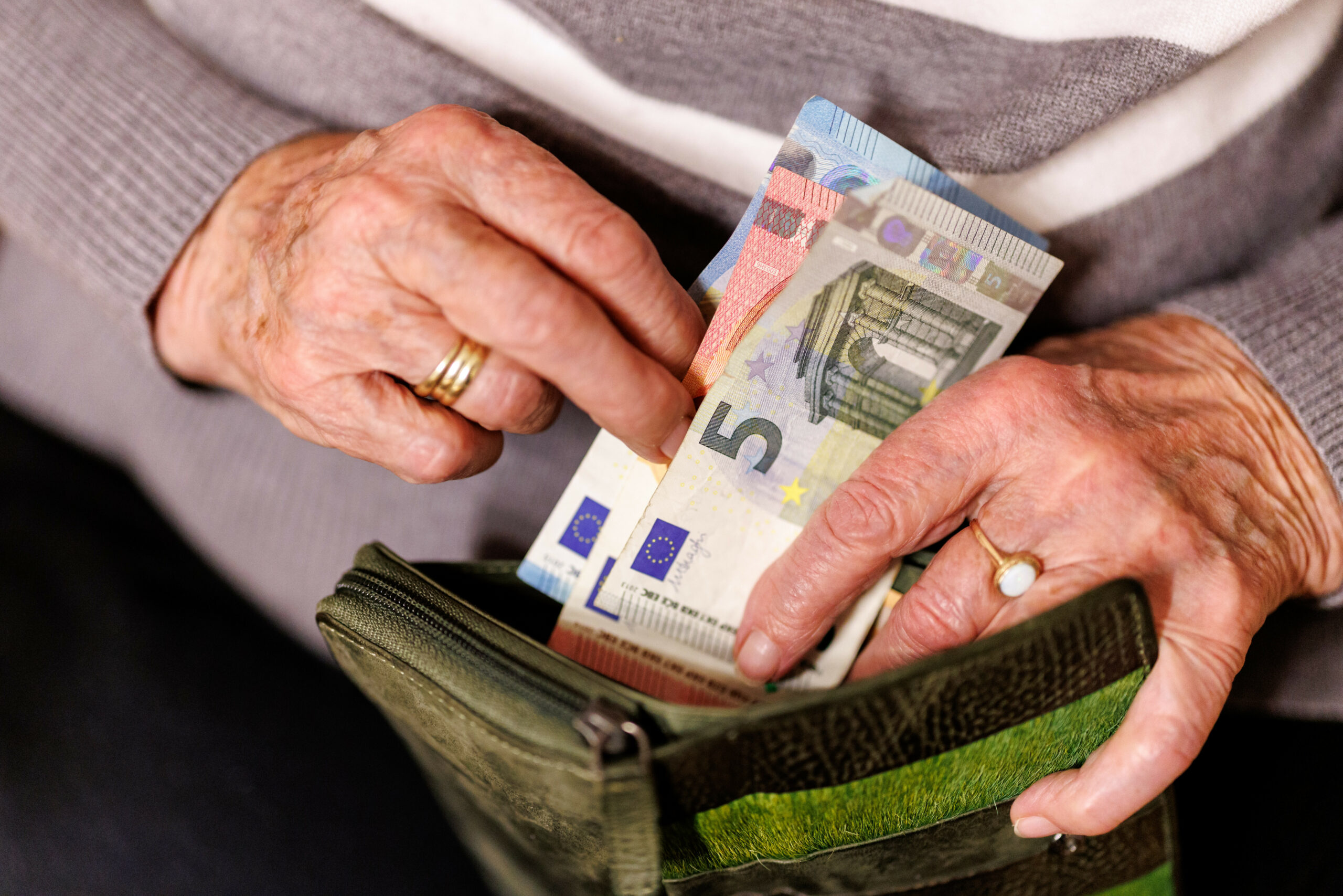 Eine Seniorin hält Geldscheine in der Hand.