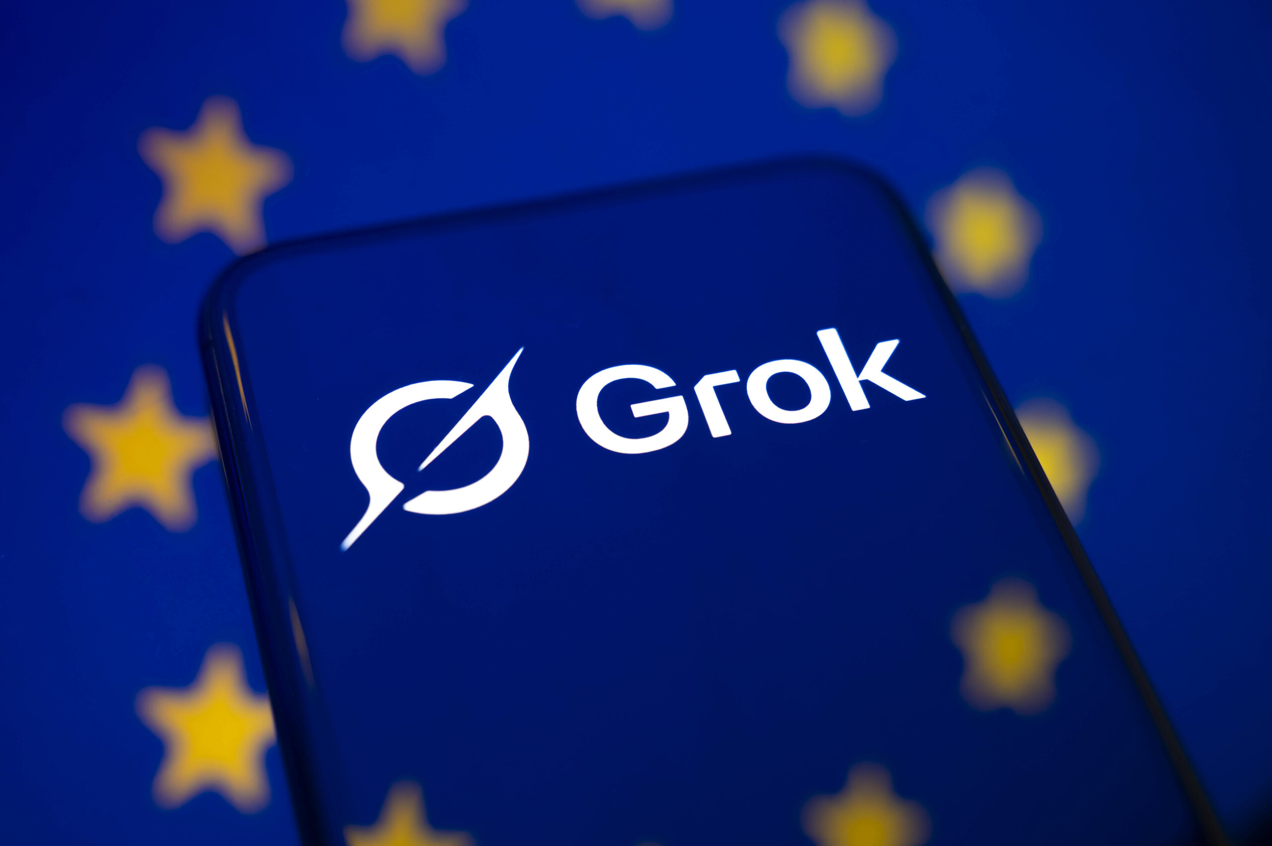 Das Logo der KI Grok vor einem Hintergrund mit den EU-Sternen. (Symbolbild)