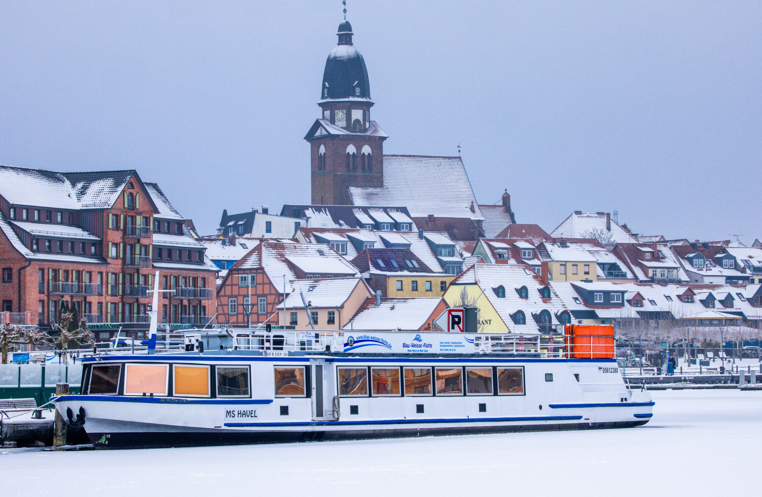 Ein Ausflugsschiff steckt im Hafen in der komplett vereisten Müritz.