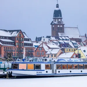 Ein Ausflugsschiff steckt im Hafen in der komplett vereisten Müritz.