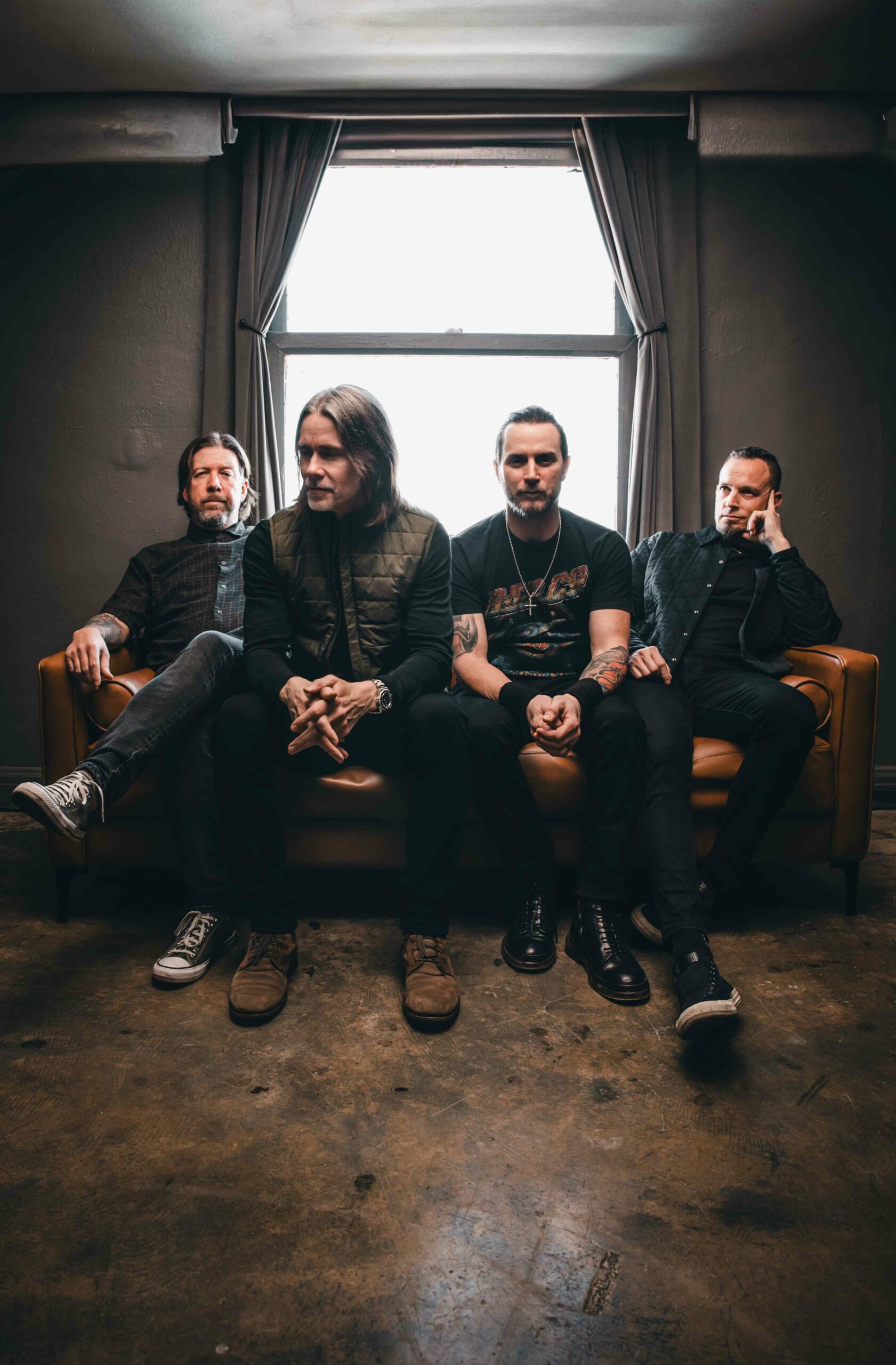 Die vier Mitglieder von Alter Bridge sitzen nebeneinander auf einem Sofa.