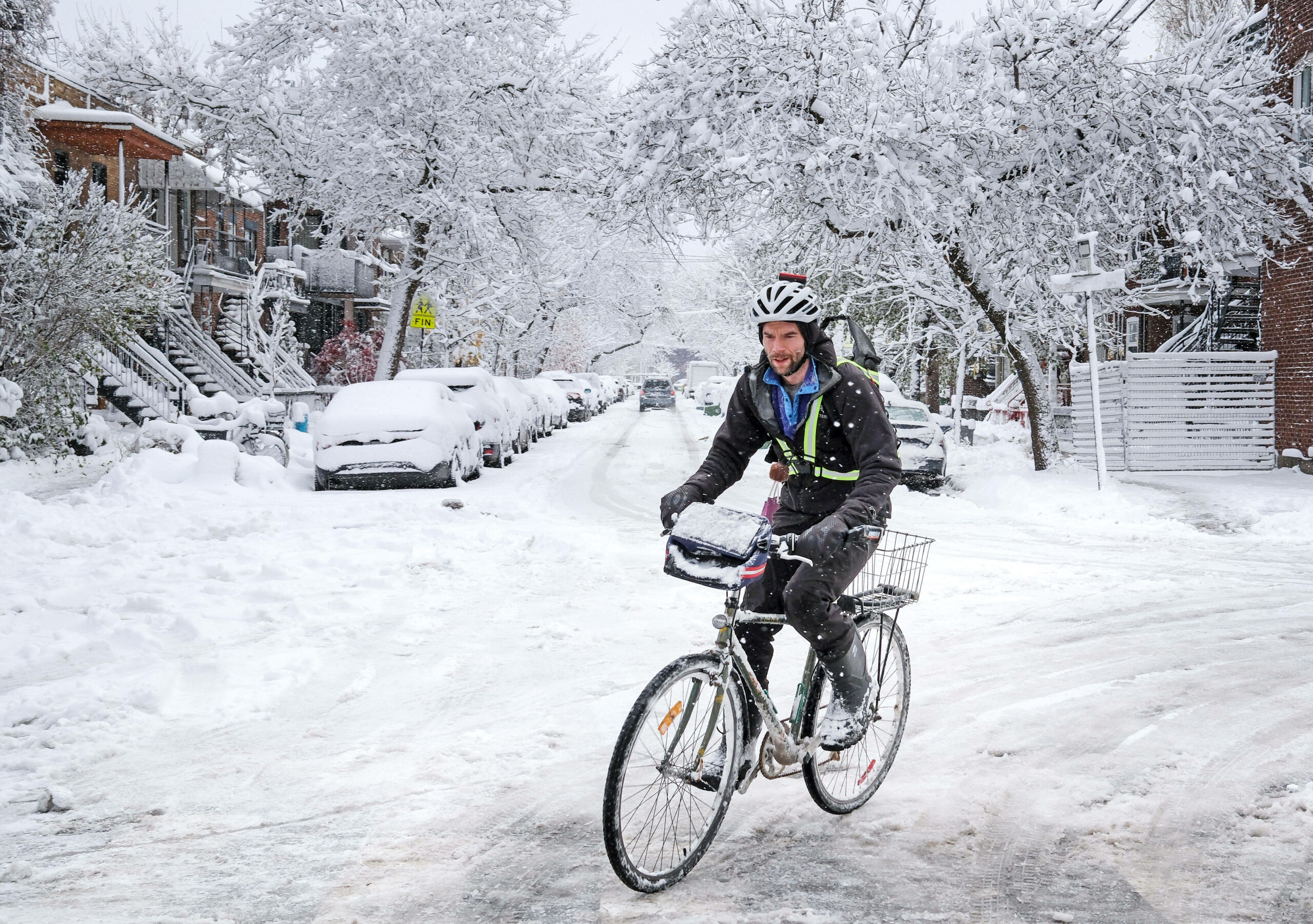 Trotz Schnee und Glätte kämpft sich ein Mann mit dem Fahrrad durch das Winterchaos auf dem Weg zur Arbeit.