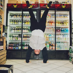 Ein Mann macht einen Handstand vor einem Kühlregal in einem Kiosk.