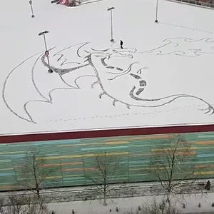 Aus dem Schnee schaut einem ein feuerspeiender Drache entgegen.