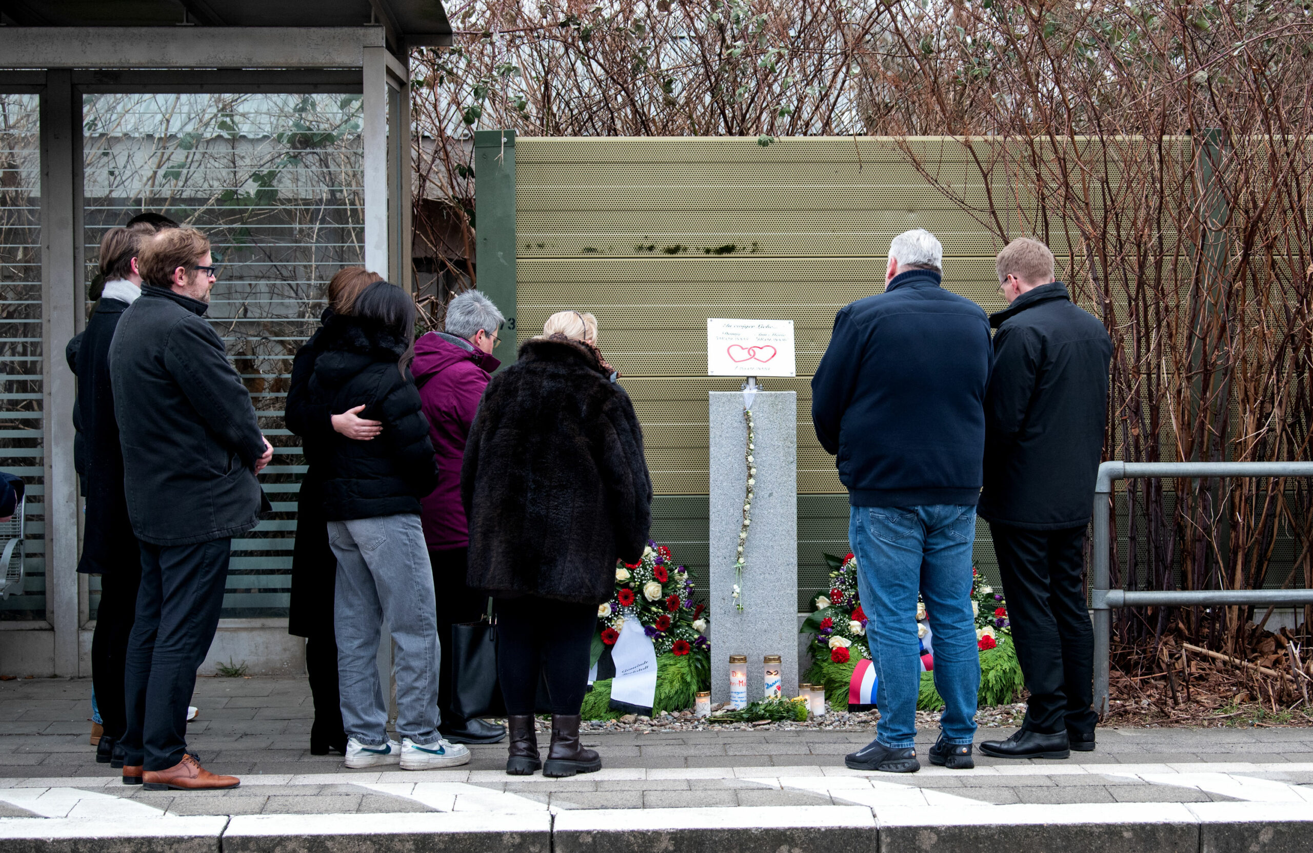 Schleswig-Holsteins Ministerpräsident Daniel Günther (r.) legt zusammen mit Michael Kyrath (2.v.r.), dem Vater eines der beiden Opfer und weiteren Angehörigen einen Kranz in Brokstedt nieder.
