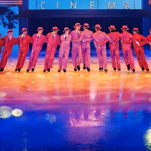 Eiskunstläufer fahren in einer Reihe vor einer Kino-Kulisse