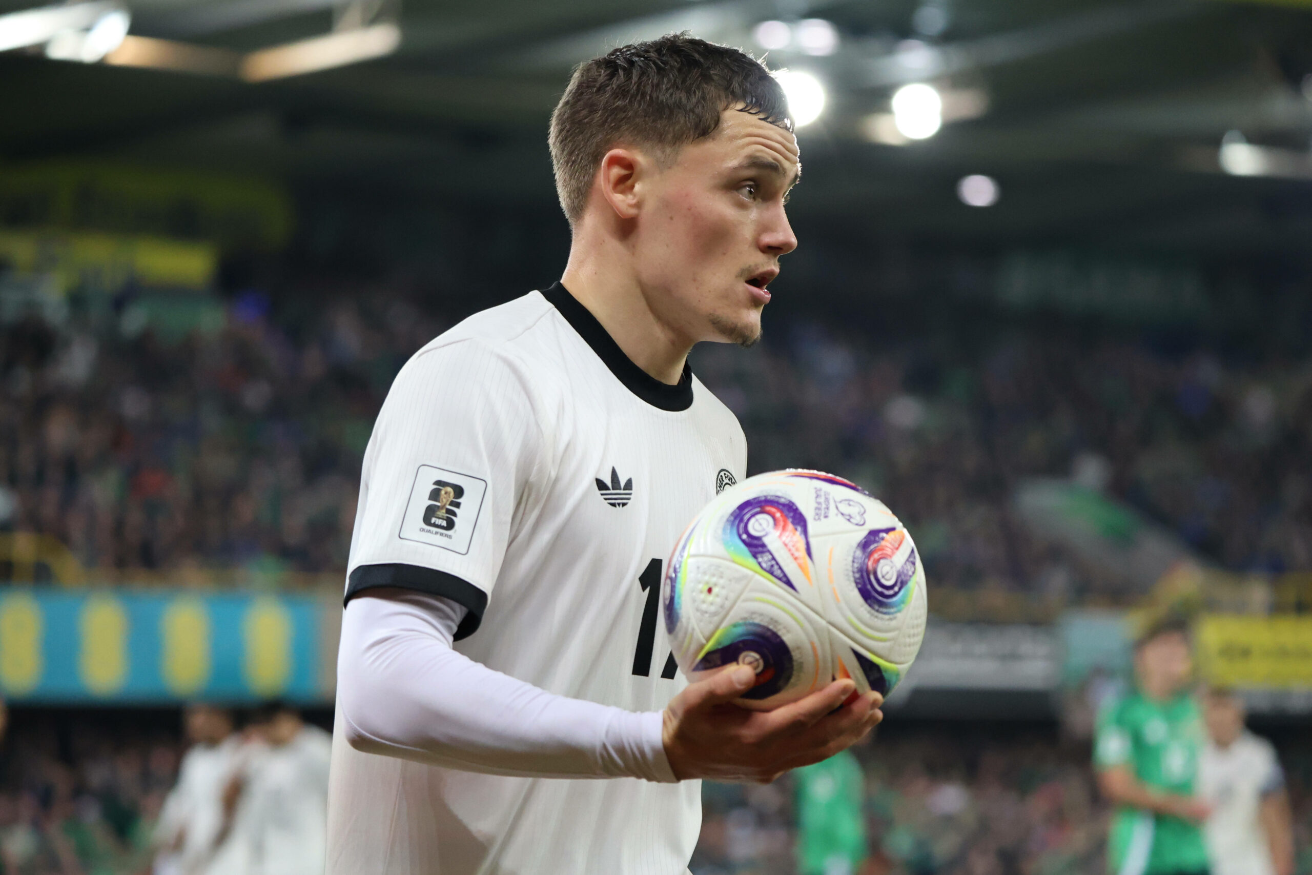 Florian Wirtz hält einen Fußball in der rechten Hand und guckt entschlossen.