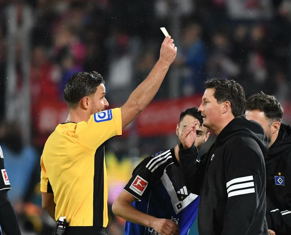 Schiedsrichter Daniel Schlager (l.) zeigt HSV-Trainer Merlin Polzin in Köln die gelbe Karte.