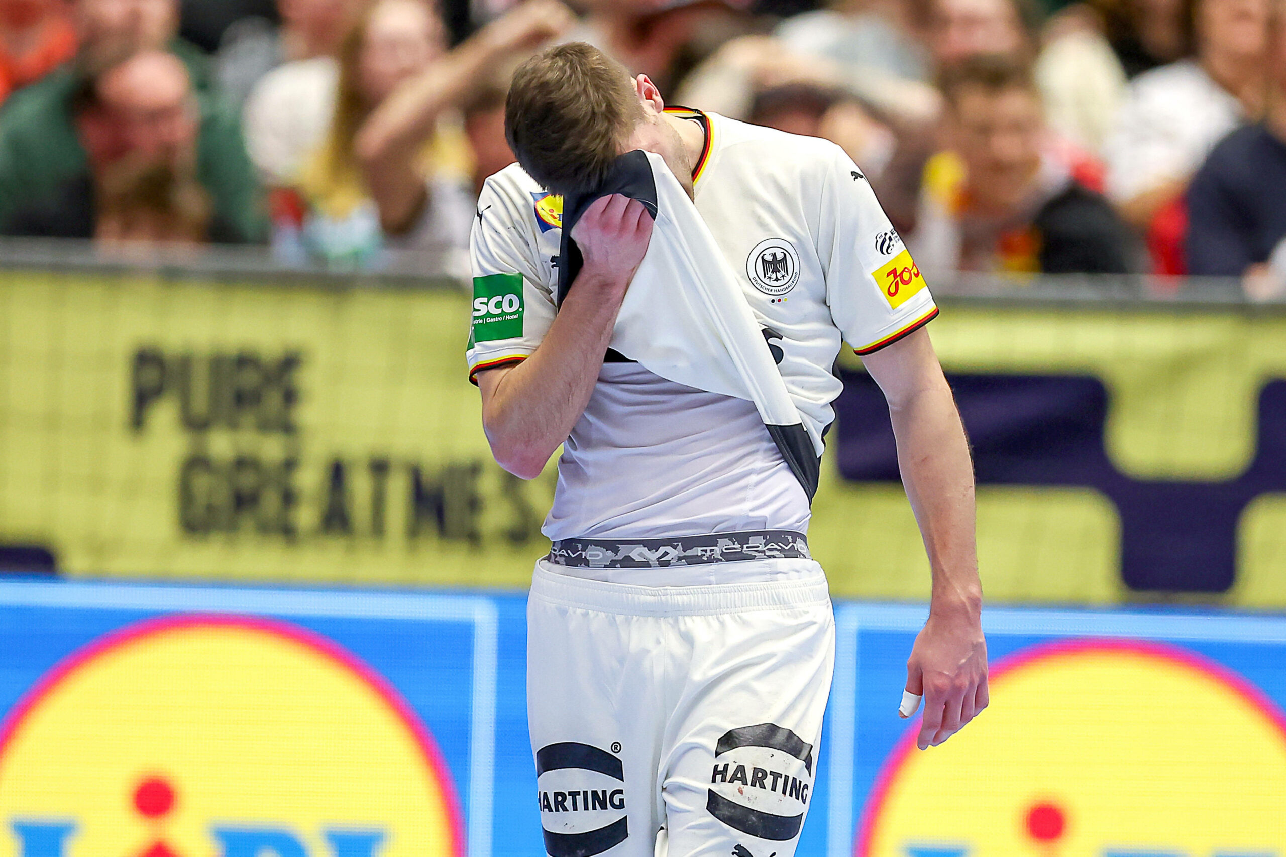 Lukas Zerbe vergräbt sein Gesicht unter seinem Trikot.