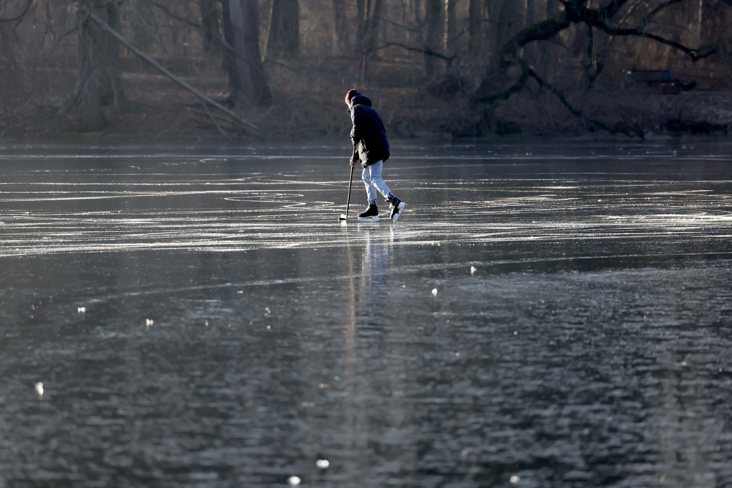 Ein Mann spielt Eishockey auf einem zugefrorenen See.