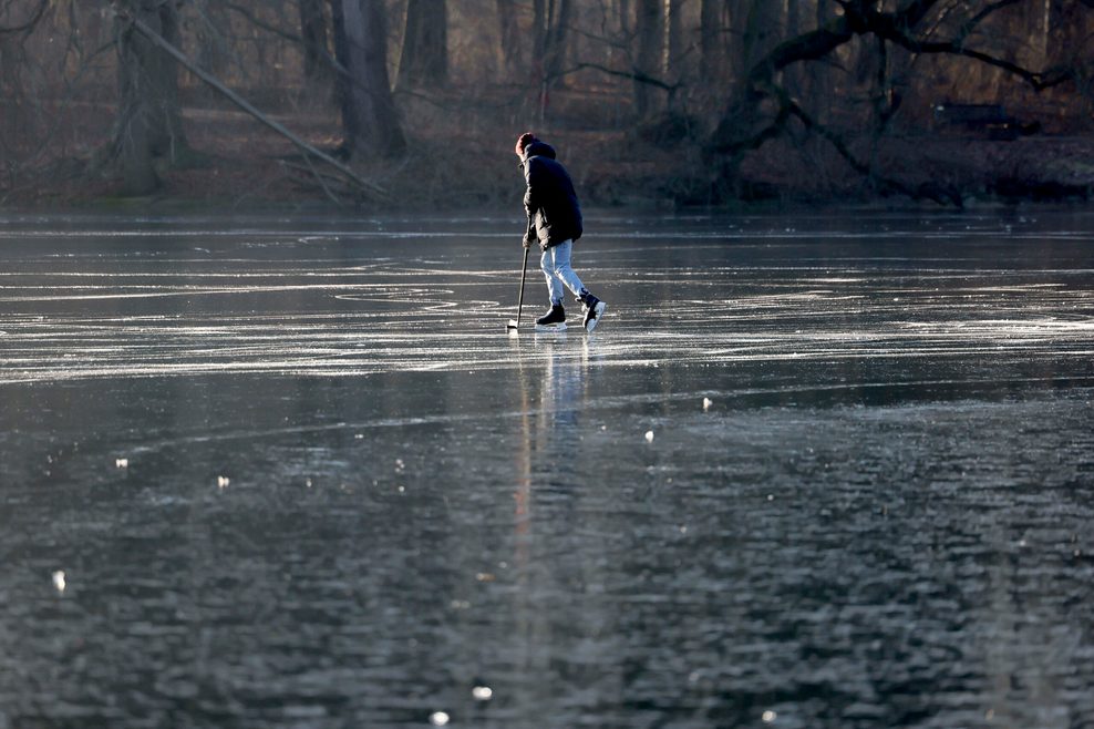 Ein Mann spielt Eishockey auf einem zugefrorenen See.