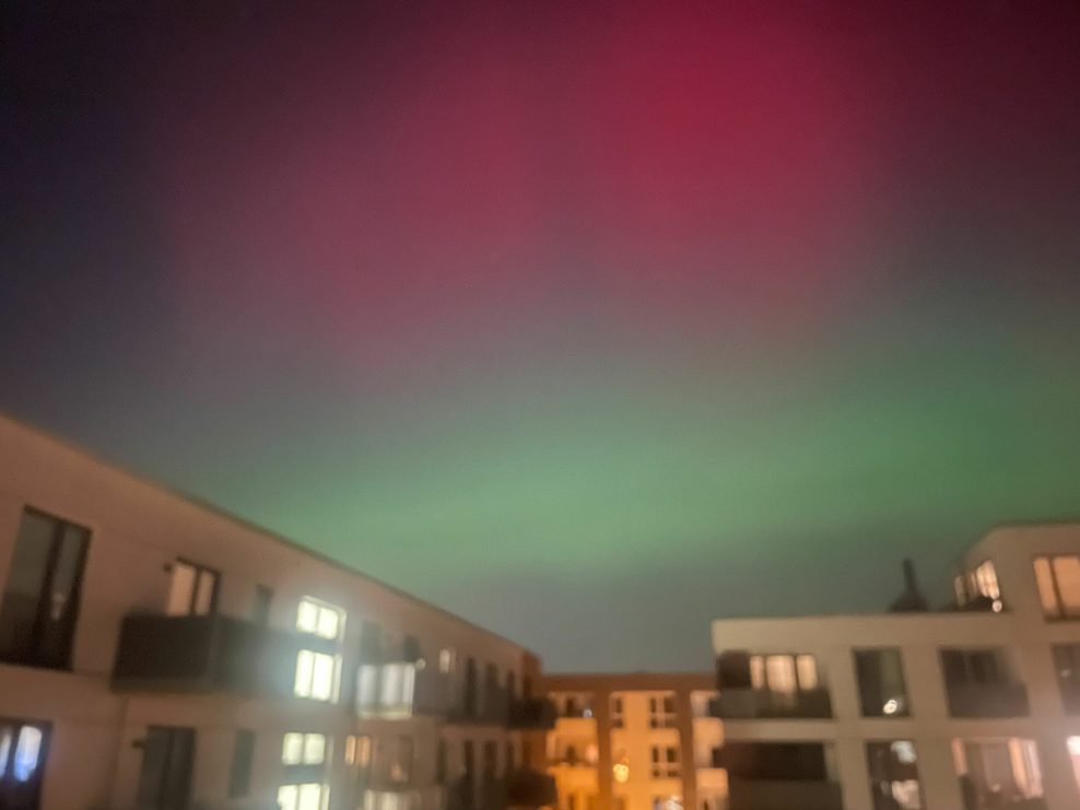 Rote und grüne Polarlichter über dem Stadtpark.
