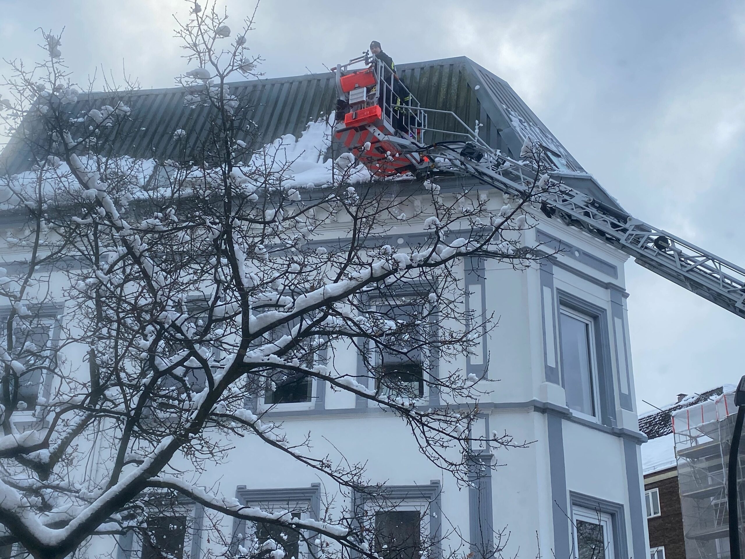 Die Feuerwehr befreit ein Dach an der Rothestraße vom Schnee.