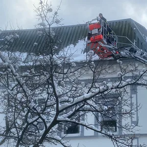 Die Feuerwehr befreit ein Dach an der Rothestraße vom Schnee.