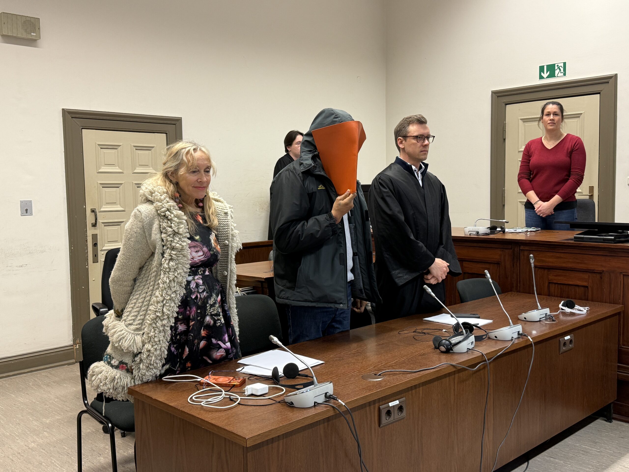 Der Angeklagte John B. steht neben seinem Ersatz-Verteidiger.