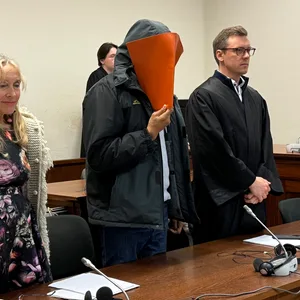 Der Angeklagte John B. steht neben seinem Ersatz-Verteidiger.