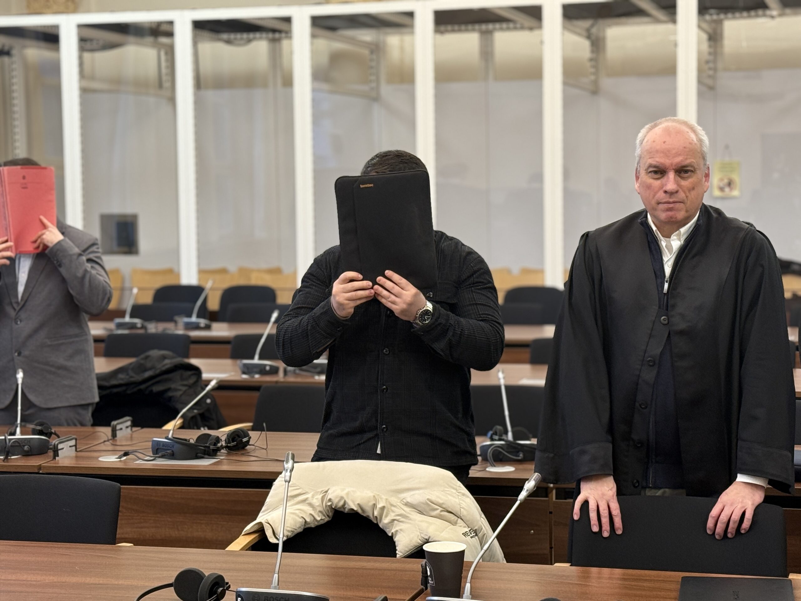 Familiendrama? Eine der Angeklagten steht neben seinem Verteidiger und verdeckt sein Gesicht.