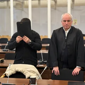 Familiendrama? Eine der Angeklagten steht neben seinem Verteidiger und verdeckt sein Gesicht.