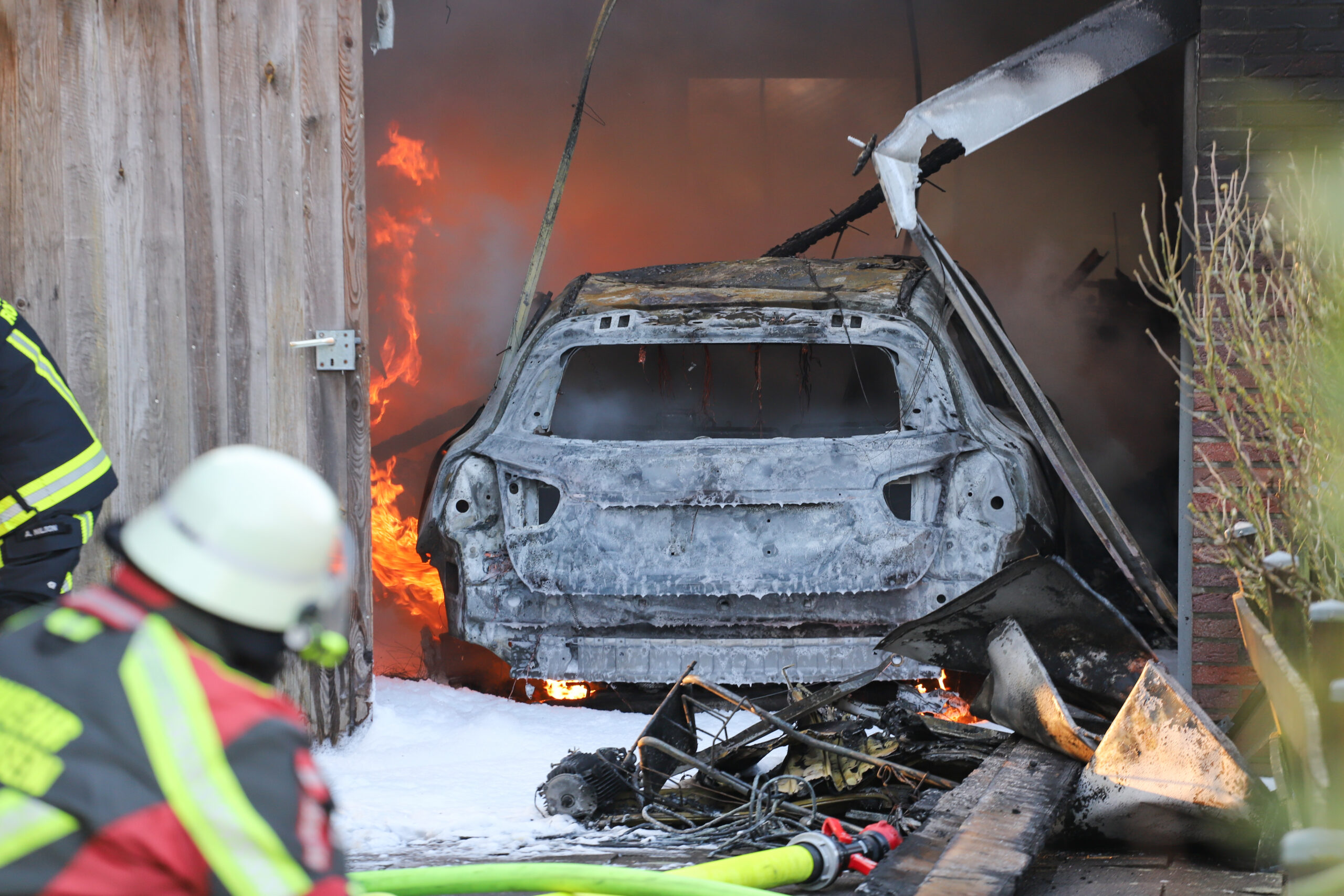 Man sieht Feuer in einer Garage und ein zerstörter Mercedes.
