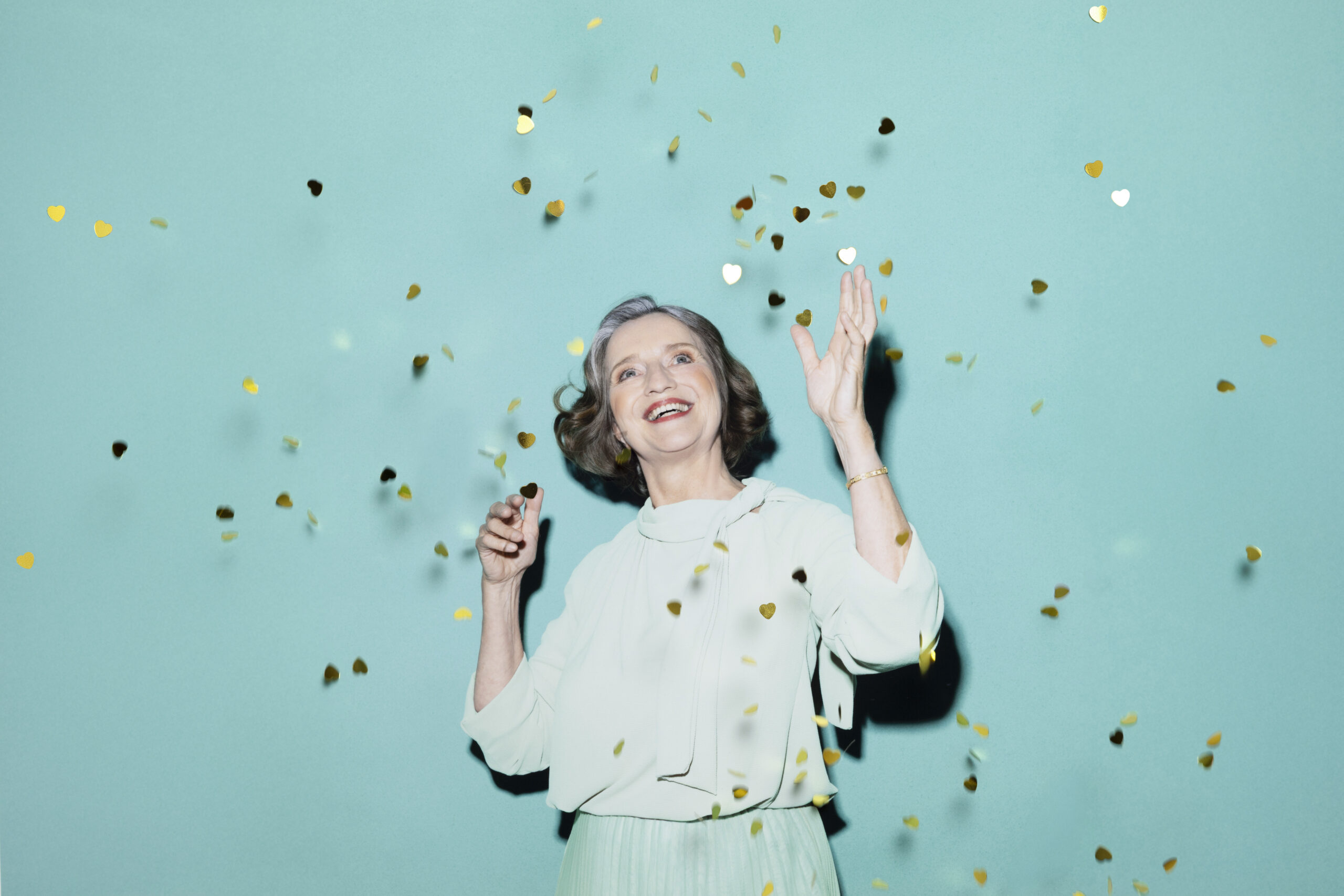 Eine Frau steht unter einem goldenen Konfetti-Regen.